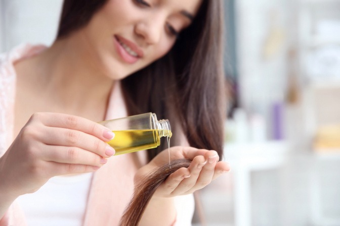 Frau gibt Öl auf ihre Haare zur natürlichen Haarpflege