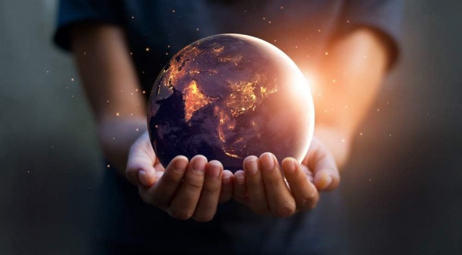 In zwei ausgestreckten Händen liegt eine Miniaturversion des Planeten Erde.  Das Modell glüht und scheint kleine Lichtblitze auszustrahlen, welche die Schwingungen der Natur symbolisieren sollen.