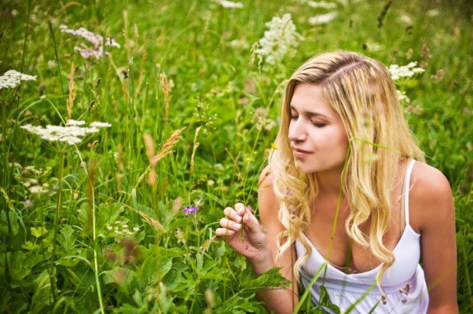 Eine Frau in der Natur riecht an Pflanzen