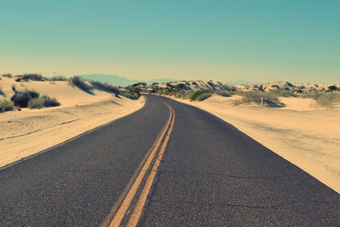 Eine leere Straße in einer Wüstenumgebung symbolisiert die Wichtigkeit von Distanz, um erfolgreich einen Neuanfang nach Trennung oder Scheidung zu vollziehen.