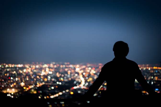 Mann sitzt in der Nacht über einer Stadt 