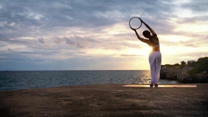 Frau im Sonnenuntergang macht Stretching-Übung
