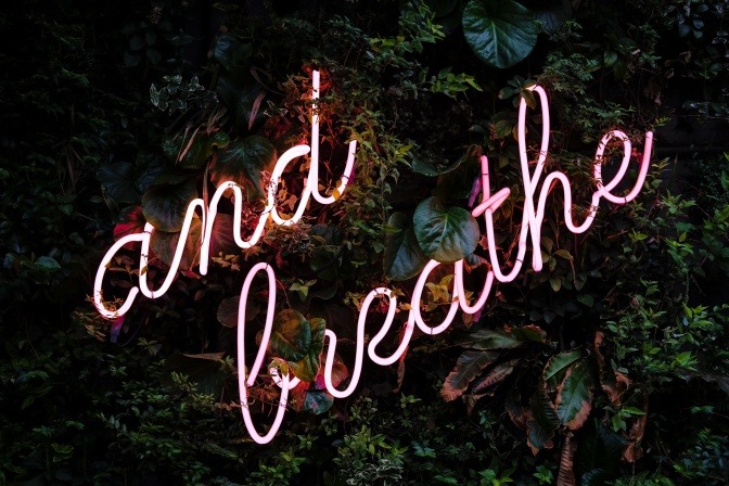 Ein Neon-Schriftzug zeigt den Spruch: and breathe.