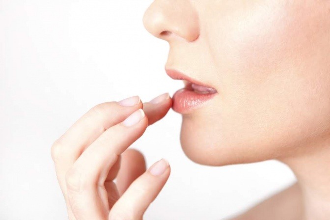 Frau greift sich an die Lippen