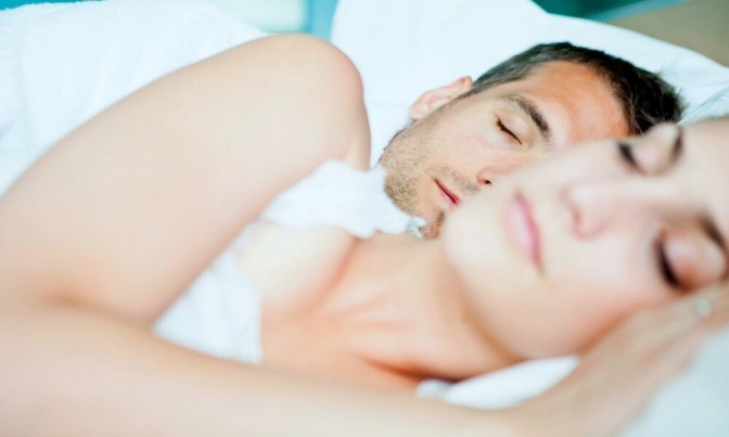Mann und Frau liegen in gemeinsamer Seitenlage im Bett