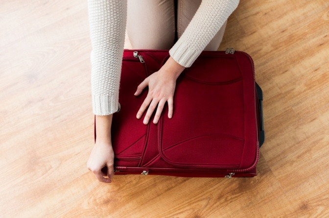 Frau packt Koffer, eventuell für Wellness-Urlaub