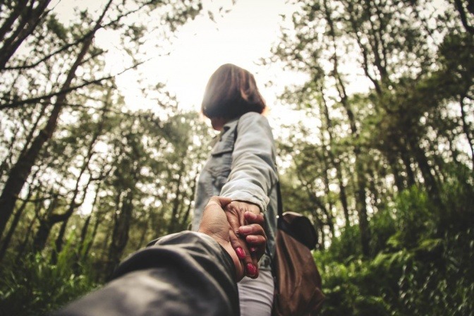 Ein Pärchen befindet sich im Wald und hält sich an den Händen