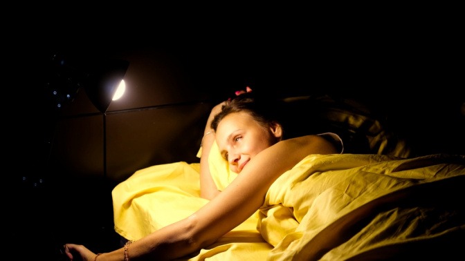 Eine Frau nachts im Bett macht Licht