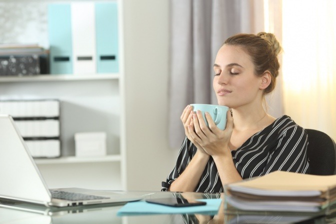 Frau im Homeoffice trinkt entspannt Kaffee