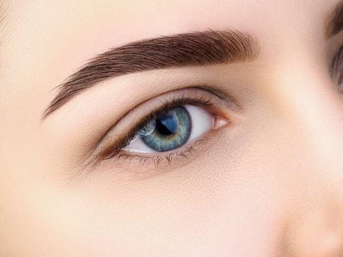 Eine perfekt geschminkte Augenbraue betont ein blaues Auge