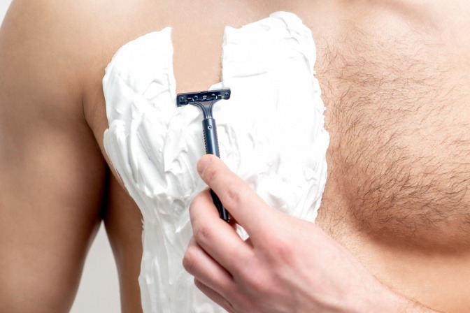 Mann rasiert sich die Brust