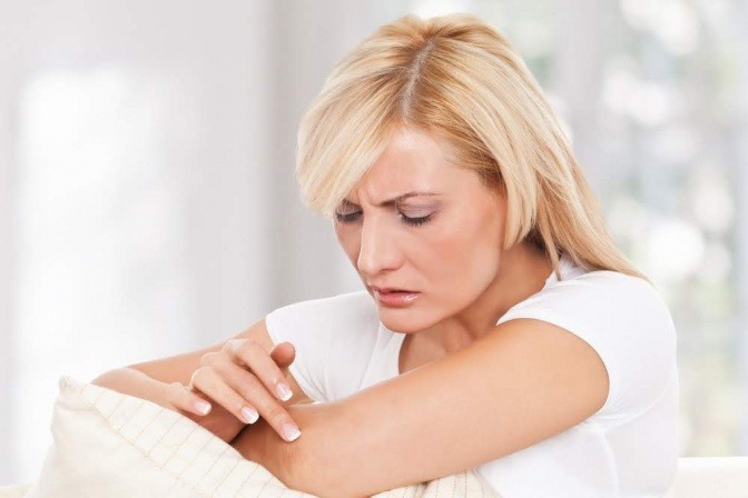 Eine Frau betrachtet die Psoriasis am Ellenbogen