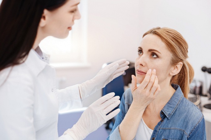 Eine Ärztin untersucht die Haut im Gesicht auf Psoriasis