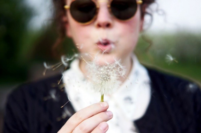 Eine Frau hält eine Pusteblume in ihren Händen