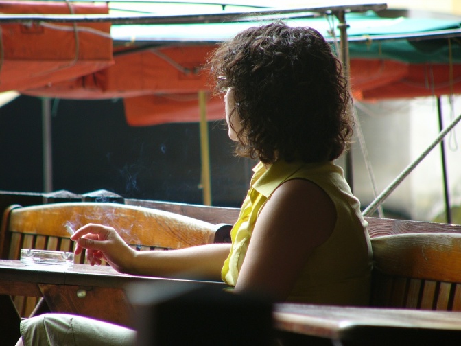 Eine Frau sitzt aus Gewohnheit beim Tisch und raucht