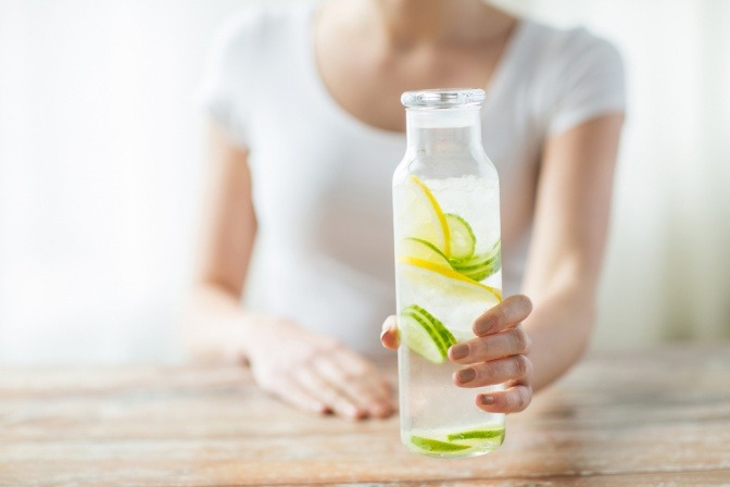 Frau mit selbstgemachtem Infused-Water in einer Glaskaraffe.