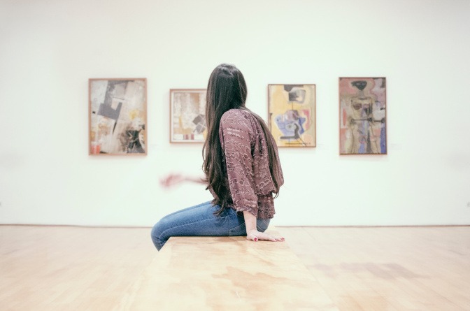 Frau im Museum sitzt auf Bank