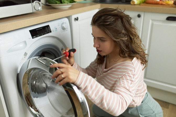Eine Frau versucht, ihre Waschmaschine zu reparieren