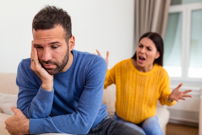 Eine Frau schreit einen traurigen Mann auf der Couch an