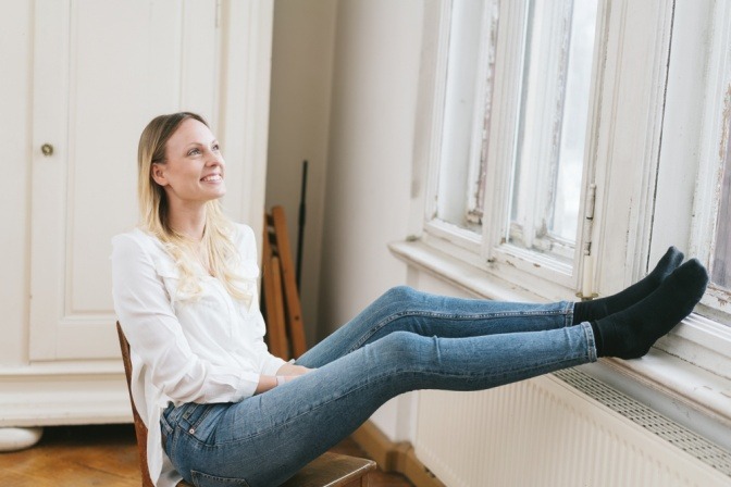 Frau vor Heizkörper bei Fenster