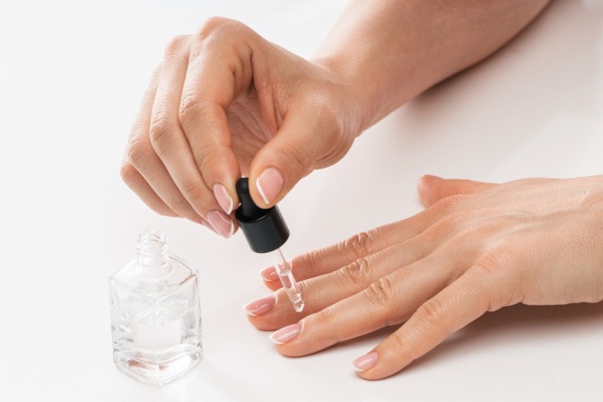 Eine Frau trägt Nagelhärter auf ihre Fingernägel auf