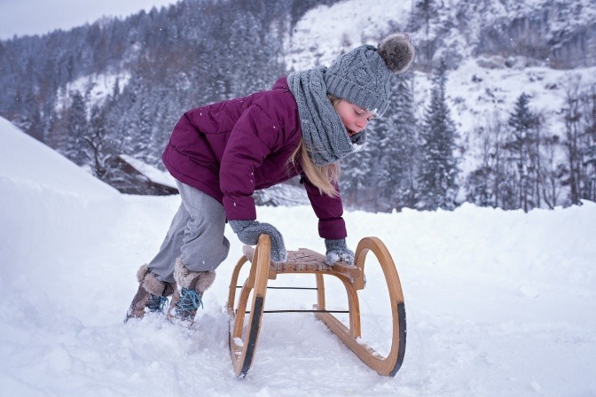 Ein Kind schiebt eine Rodel im Winter