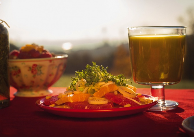 Ein Glas mit Smoothie steht neben einem Teller mit Rohkost