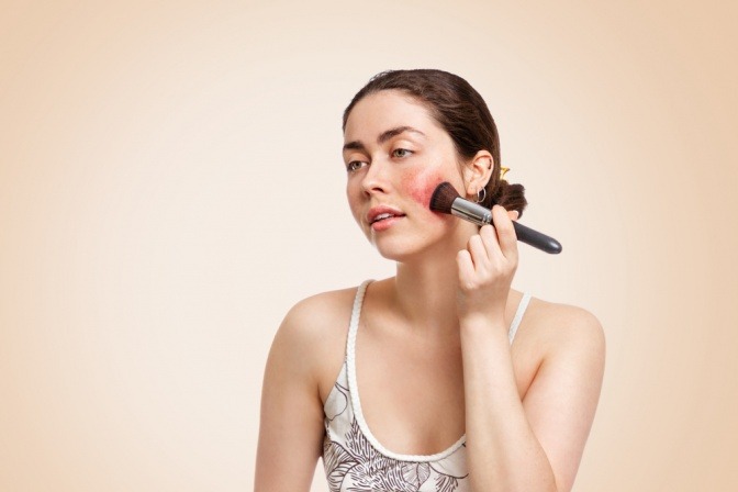 Eine Frau mit Rosacea trägt Make-up auf