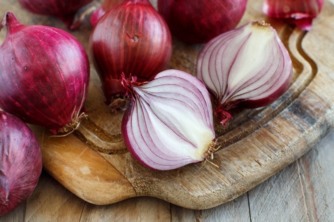 Rote Zwiebeln liegen auf einem Schneidebrett