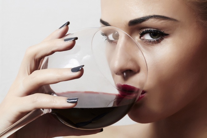 Frau trinkt aus Rotwein.