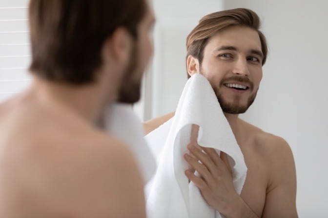 Mann reinigt mit einem Handtuch sanft seine Haut