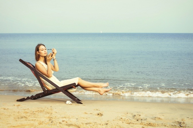 Frau schminkt sich am Strand