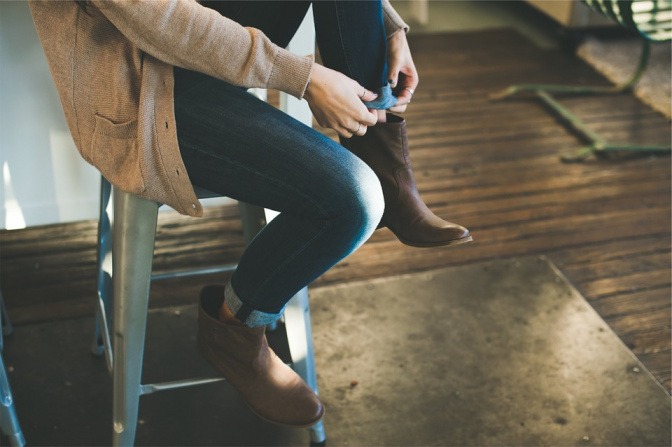 Eine Frau sitzt auf einem Hocker und zieht sich die Schuhe an