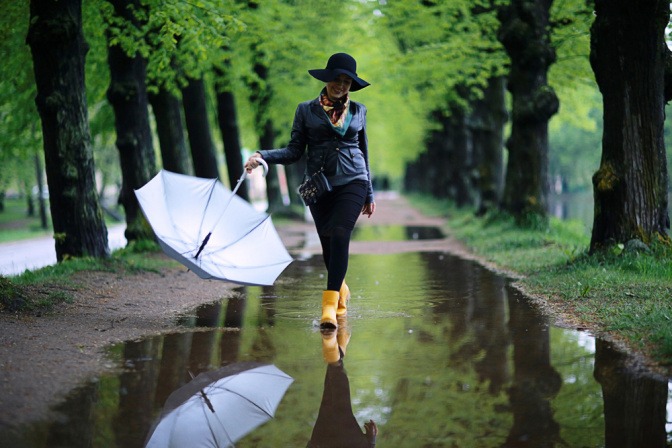 Schuhe wasserdicht machen - Frau läuft durch eine große Pfütze in einer Allee.