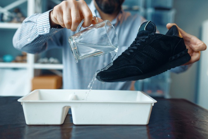 Mann kippt Wasser über Schuhe um Wasserdichtigkeit zu testen.