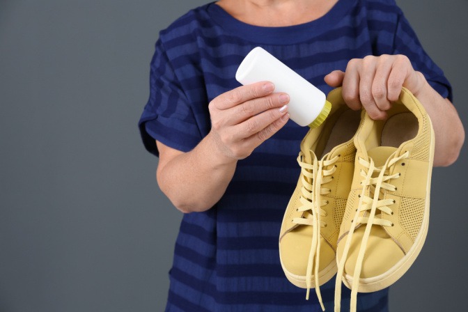 Frau gibt Talkum-Puder in Schuhe, um das Quietschen der Sohlen zu beseitigen.
