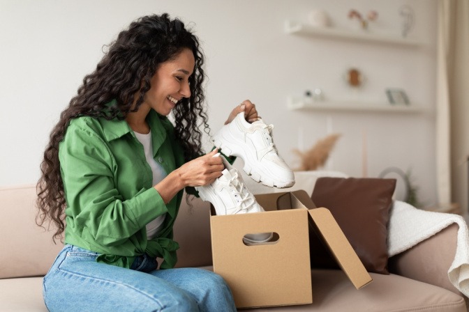 Frau packt weiße Sneaker aus einer Schachtel aus