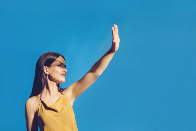 Frau schützt sich mit der Hand vor der Sonne