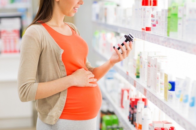 Eine schwangere Frau steht vor einem Regal mit Medikamenten