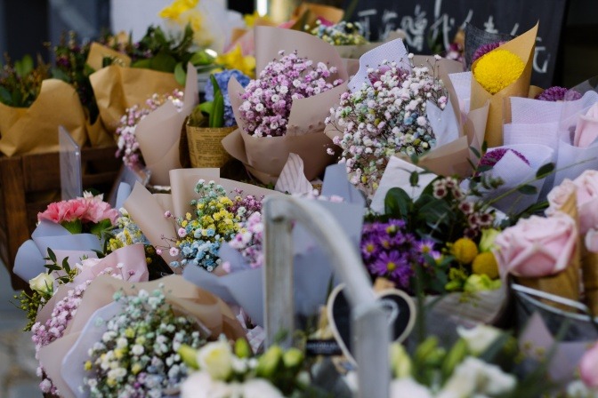 Diverse Blumensträuße mit Wiesenblumen vor dem Eingang eines Ladens.