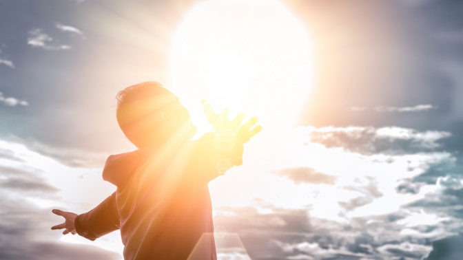 Eine Frau steht selbstzentriert vor Sonnenschein