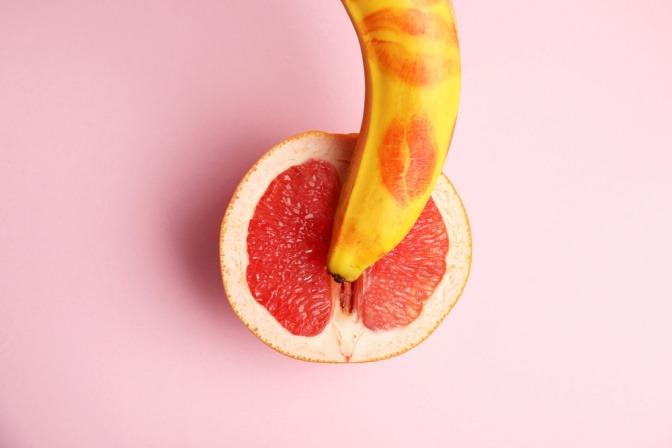 Aufgeschnittene Grapefruit und Banane mit Lippenstift darauf. 