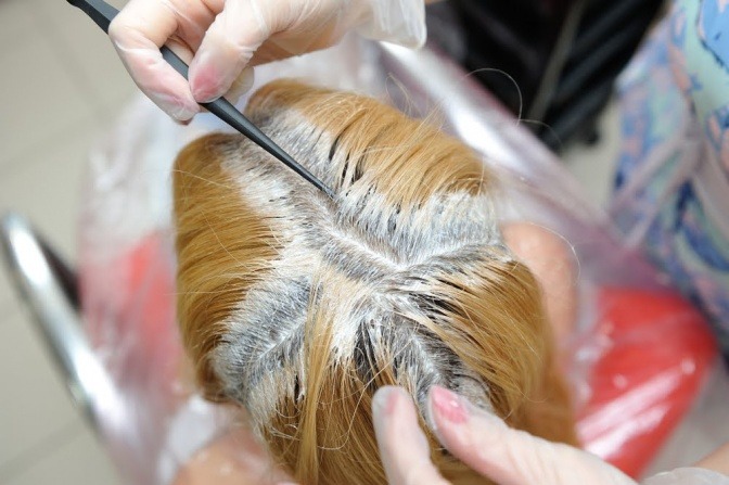 Ein Frauenkopf mit blondiertem Haar, wobei der Ansatz gerade aufblondiert wird