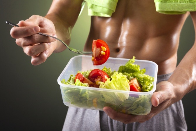 Ein Mann mit einem Sixpack isst Salat