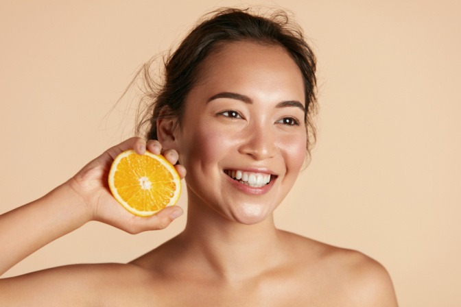 Eine Frau hält eine halbe Orange in der Hand