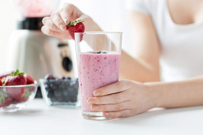 Eine Frau süßt einen Smoothie 