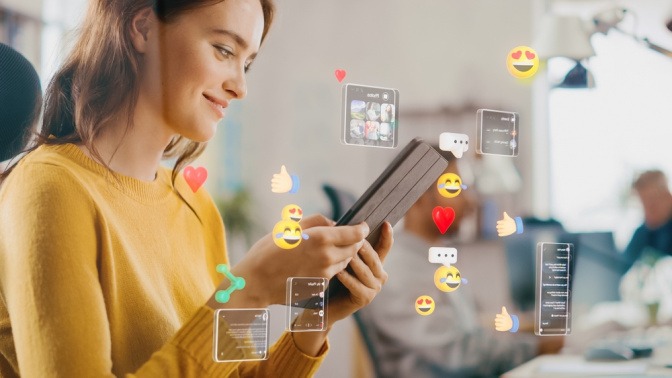 Lächelnde Frau tippt auf ihrem Smartphone, im Vordergrund sind Emojis eingeblendet