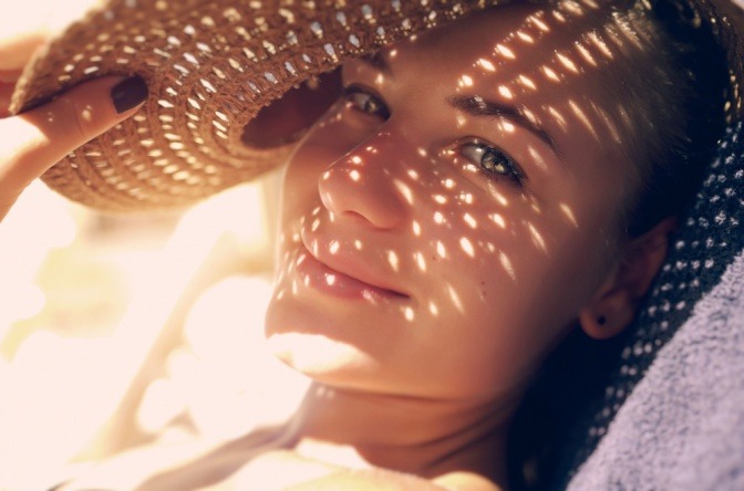 Frau mit Hut und Punkten von der Sonne im Gesicht