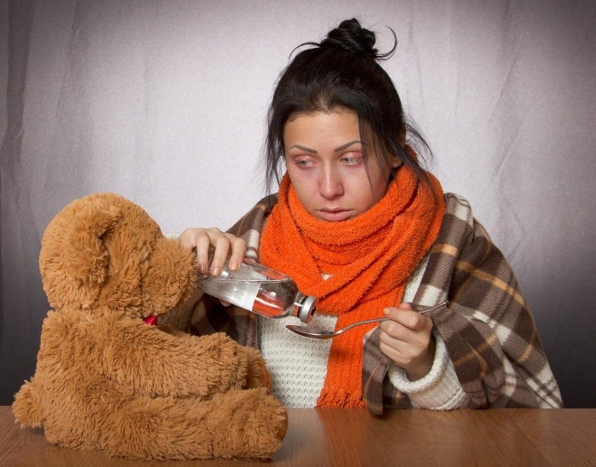Frau mit Sommergrippe mit Medizin und Teddybär