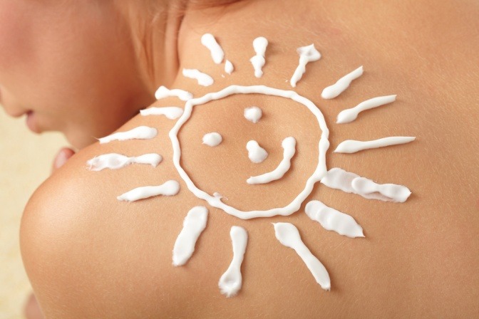 Eine Frau hat eine mit Sonnencreme gezeichnete Sonne auf der Schulter